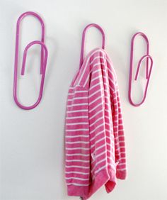 two pink towel hooks are hanging on a white wall next to a pink and white striped towel