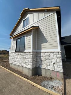 a house that is being built in the middle of some dirt and grass with a blue sky behind it