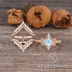 three pieces of gold jewelry sitting on top of a wooden table next to dried flowers