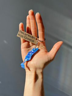 a hand holding a keychain with a piece of blue glass in it's palm