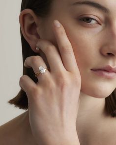 a woman holding her hand to her face with a diamond ring on her left hand