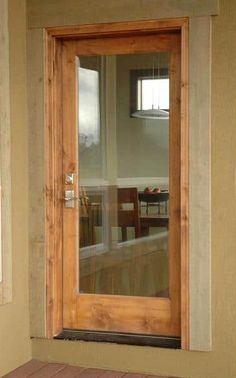 an empty room with a wooden door and glass window on the outside wall, in front of a dining table