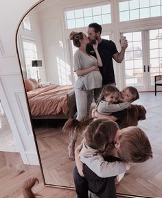 a man taking a photo of himself and his family in front of a large mirror