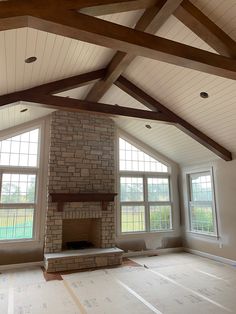 an empty living room with large windows and a brick fireplace in the middle of it