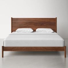 a bed with white pillows and wooden headboard