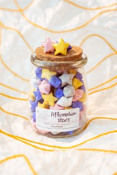 a jar filled with colorful stars on top of a table