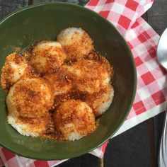 a green bowl filled with food on top of a red and white checkered table cloth