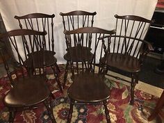 four antique windsor style dining chairs, all in different sizes and colors on a rug