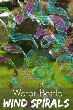 a wind spiral made out of glass sitting on top of a grass covered field with text overlay that reads water bottle wind spirals