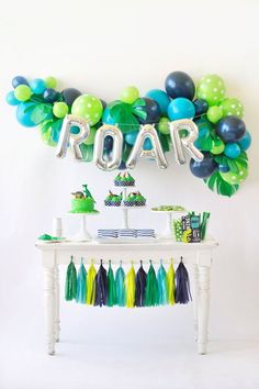 a table topped with balloons and cake next to a sign that says roar on it