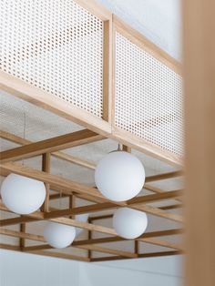 three white balls hanging from the ceiling in a room with wood beams and perfored panels