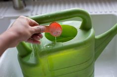 a person is pouring liquid into a green watering can