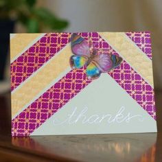 a thank card with a butterfly on it sitting on a table next to a potted plant