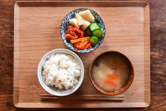 a wooden tray topped with two bowls filled with food