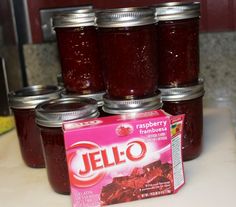 four jars of jello sitting on top of a counter next to a carton of jelly