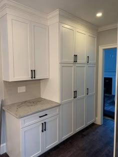 an empty kitchen with white cabinets and marble counter tops