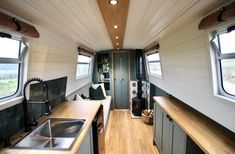 the interior of an rv with wood flooring and white walls, along with two windows