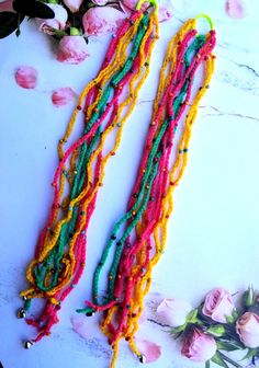 two strands of multicolored beaded necklaces next to flowers on a table