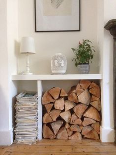 a stack of firewood sitting on top of a white shelf next to a lamp