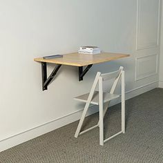 a desk with a chair underneath it and a book on the top shelf next to it