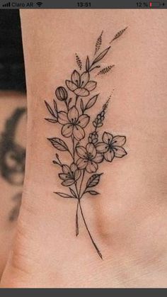 a small flower tattoo on the side of a woman's stomach, with leaves and flowers