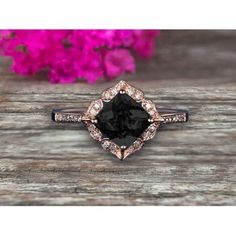 a black diamond ring with white diamonds on the side and pink flowers in the background