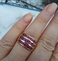 a woman's hand with a gold and pink ring on it