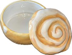 a white and gold bowl with a spiral design in it's center, on a white background