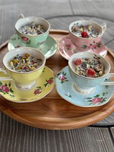 four cups and saucers filled with food on top of a wooden tray