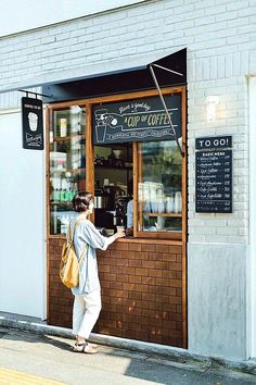 a woman standing in front of a coffee shop with her hand on the door window