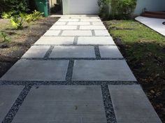 a walkway made out of stones in front of a house with a garage door on the other side