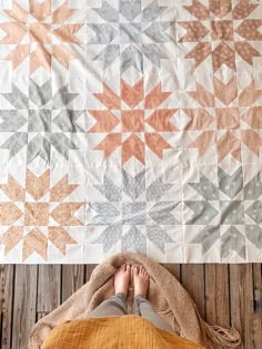 a person laying on top of a wooden floor next to a quilt