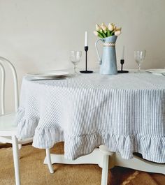 a dining room table with white chairs and a blue vase filled with tulips