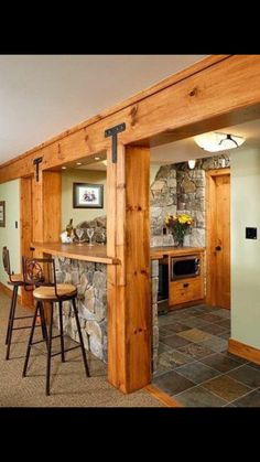 a living room filled with furniture next to a stone wall and wooden beams on the ceiling