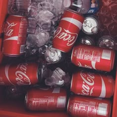 a red cooler filled with lots of coca - cola cans and ice cubes in it