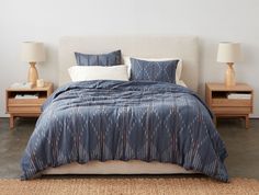 a bed with two nightstands next to it and a blue comforter on top