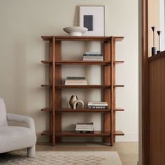 a room with a chair, bookshelf and pictures on the wall