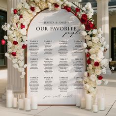 a wedding seating chart with white and red flowers on the front, surrounded by candles