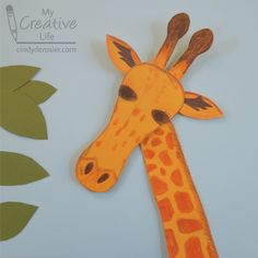 a paper cut out of a giraffe's head with leaves around it