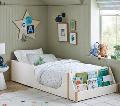 a child's bedroom with green walls, white bedding and pictures on the wall