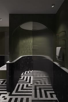 a bathroom with black and white tile flooring next to a bathtub in the corner