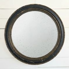 a round mirror hanging on the side of a white wall next to wood planks