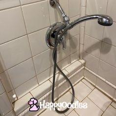 a shower head in the corner of a tiled bathroom with white tile walls and floor