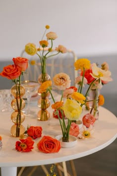 an arrangement of flowers on a table with gold vases and glass balls in the center