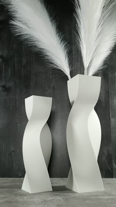 two tall white vases with feathers in them