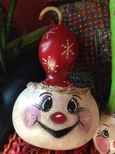 a close up of a rock with a clown face on it and a potted plant in the background