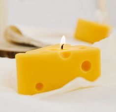 a candle that is on top of a white sheet with some cheese in the background