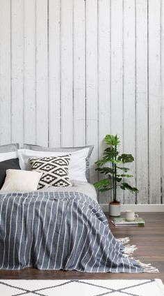 a bed with pillows and blankets on top of it next to a potted plant