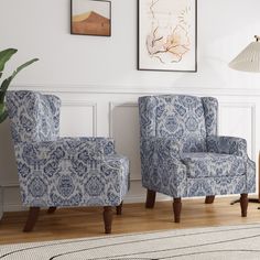 two blue chairs sitting next to each other on top of a hard wood floor in front of a white wall