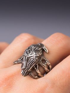 a close up of a person's hand wearing a ring with a bird on it